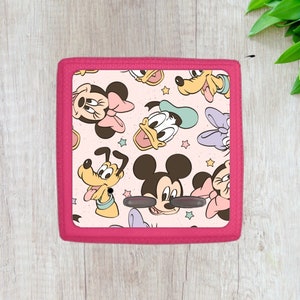 May include: Pink fabric storage box with a pink border and a pattern of Mickey Mouse, Minnie Mouse, Donald Duck, and Goofy characters on a light pink background.
