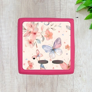 May include: A pink case with a floral design featuring butterflies and hearts. The case has a cream background with pink, white, and blue butterflies.