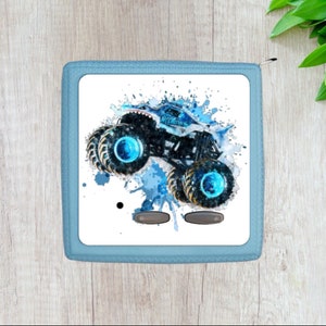 May include: A blue zippered pouch with a white background featuring a blue monster truck with blue wheels and a blue and white watercolor splash design.