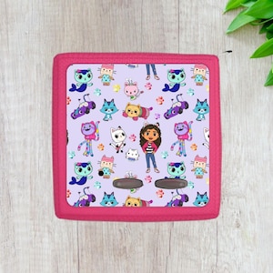 May include: A pink and purple patterned case with a cartoon girl and cats. The case has a purple background with pink trim and features a variety of cartoon characters, including a girl with brown hair and a pink shirt, a cat with a pink bow, and a cat with a blue bow.