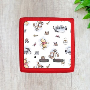 May include: Red phone case with a white background and a repeating pattern of Winnie the Pooh and Piglet characters. The characters are in various poses, including playing instruments and holding honey pots.
