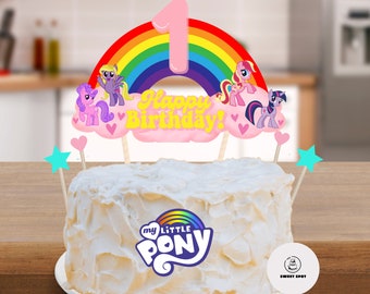 Pode incluir: Um bolo branco com um logotipo do My Little Pony e um topo de bolo temático de arco-íris e unicórnio que diz "Feliz aniversário!"