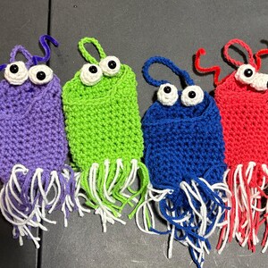 May include: Four crocheted amigurumi creatures with googly eyes and fringe. The creatures are purple, green, blue, and red.