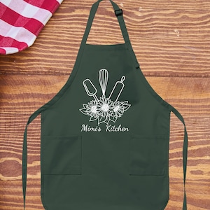 May include: A dark green kitchen apron with a white design of kitchen utensils and sunflowers. The text "Mimi's Kitchen" is printed below the design.