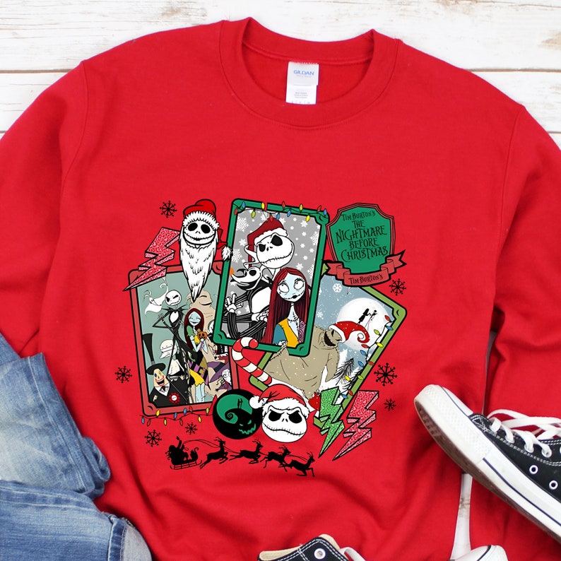 May include: A red sweatshirt featuring a graphic design from "The Nightmare Before Christmas." The design includes images of Jack Skellington, Sally, and other characters, along with snowflakes and lightning bolts. The text "The Nightmare Before Christmas" is also visible.