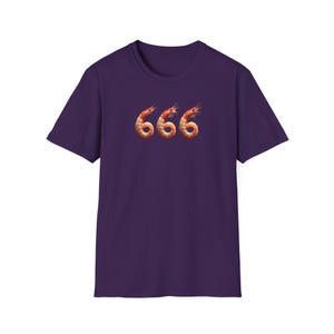 May include: A purple t-shirt with a graphic of three shrimp forming the number 666. The shrimp are orange and brown, with detailed textures. The shirt has a crew neck and short sleeves, and is a solid colour.