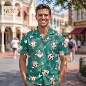 May include: A short-sleeved button-down shirt in teal green featuring an all-over Christmas print of Disney characters including Mickey Mouse, Minnie Mouse, Donald Duck, and Goofy wearing Santa hats, interspersed with snowflakes and castle icons.