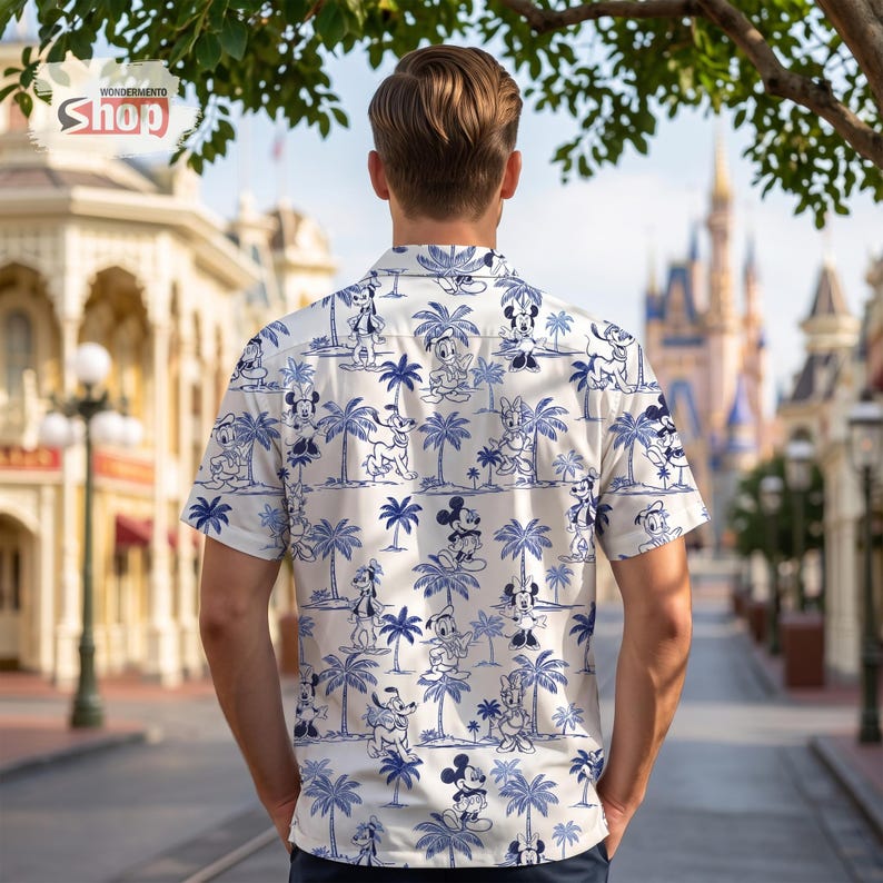 May include: A short-sleeved button-down shirt featuring an all-over blue and white print of Disney characters including Mickey Mouse, Minnie Mouse, Donald Duck, and Pluto interspersed with palm trees. The shirt has a collar and a buttoned front.
