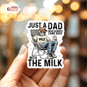 May include: A white sticker with a cartoon skeleton sitting in a camping chair and holding a carton of milk. The text on the sticker reads 