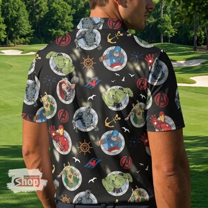 K&ouml;nnte beinhalten: Schwarzes Poloshirt mit einem sich wiederholenden Muster von Marvel-Charakteren in kreisf&ouml;rmigen Rahmen. Das Design umfasst Captain America, Hulk, Iron Man, Thor und Black Panther sowie Anker, Steuerr&auml;der und das Avengers-Logo.