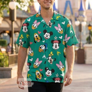 May include: Green button-up shirt featuring a repeating pattern of Mickey Mouse, Donald Duck, Daisy Duck, and Goofy. The short-sleeved shirt has a camp collar and is made of a lightweight fabric. The shirt is a fun and colorful addition to any wardrobe.