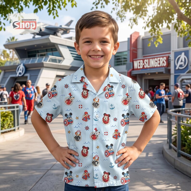 May include: A light blue short-sleeved button-down shirt featuring an all-over print of various cartoon characters, including Mickey Mouse and Spider-Man, interspersed with nautical icons like anchors, life preservers, and ship wheels.