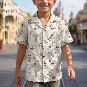 May include: Cream-colored button-down shirt featuring a repeating black and white cartoon character pattern. The shirt has short sleeves and a collared neckline. The Wondermento Shop logo is visible in the upper left corner.