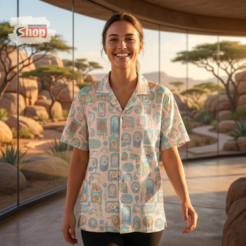 May include: A short-sleeved button-down shirt with a light pink background and a repeating pattern of cartoon-style illustrations in blue, brown, and beige. The shirt has a collared neckline and is worn by a person. The Wondermento Shop logo is in the top left.