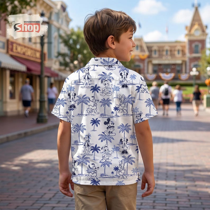 May include: A short-sleeved button-down shirt in white with a repeating blue pattern of cartoon characters and palm trees. The shirt features a classic collar and a button-up front, showcasing a tropical-inspired design with various figures.