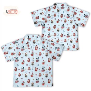 May include: A light blue short-sleeve button-down shirt featuring an all-over print of cartoon characters including Mickey Mouse and Spider-Man, interspersed with nautical symbols like anchors, ship wheels, and life preservers on a white background.