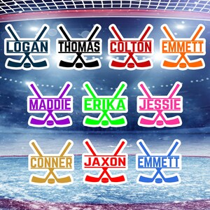 May include: Nine hockey stick decals with personalised names. The decals are in various colours, including blue, black, red, orange, purple, green, pink, gold, and light blue. The names on the decals are Logan, Thomas, Colton, Emmett, Maddie, Erika, Jessie, Conner, Jaxon, and Emmett.