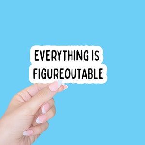 May include: A white sticker with black text that reads "Everything is Figureoutable" held by a hand with white nail polish.