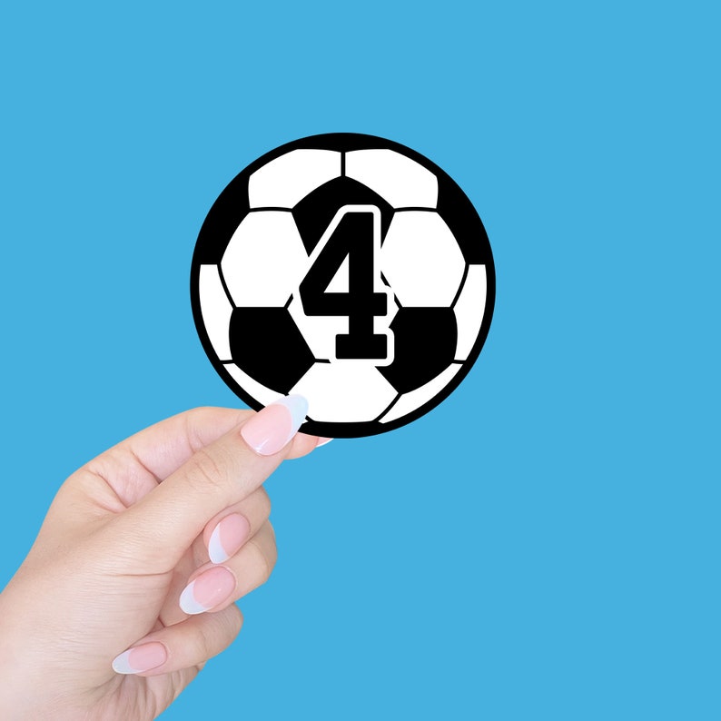May include: A black and white soccer ball with the number 4 printed on it. The ball is being held by a hand.