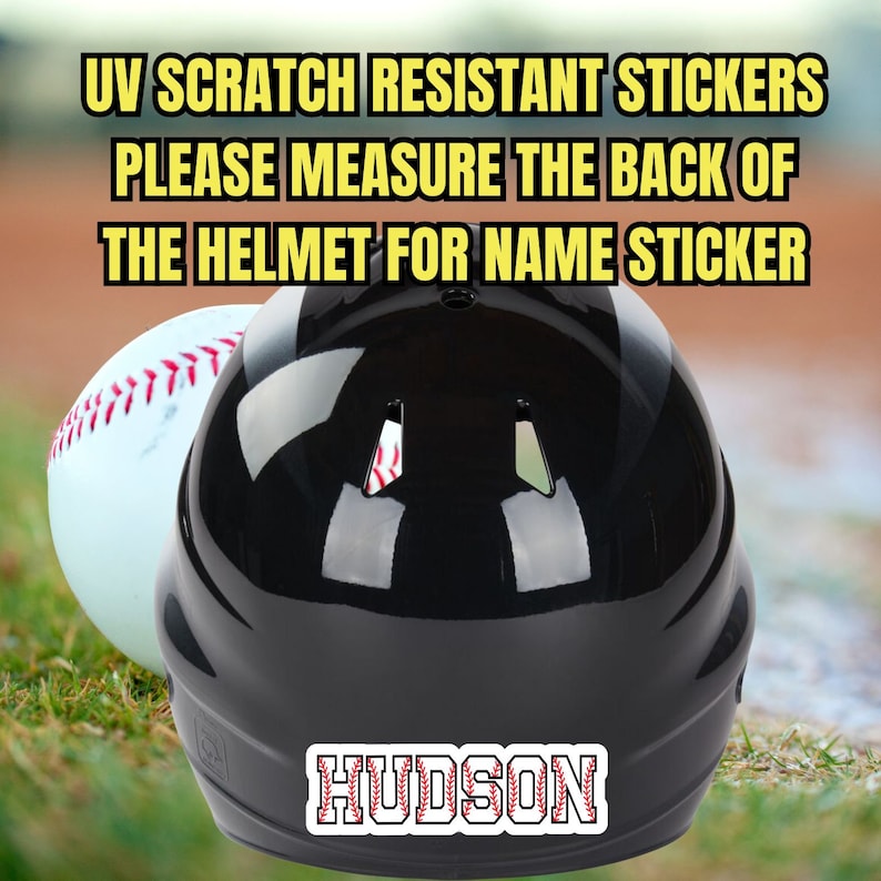 May include: Black baseball helmet with a white baseball next to it. The helmet has a red and white baseball stitch design on the back with the name "HUDSON" in white letters.