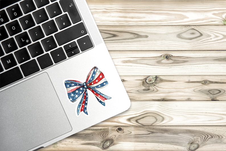 May include: A red, white, and blue bow with stars on the fabric. The bow is on a silver laptop.