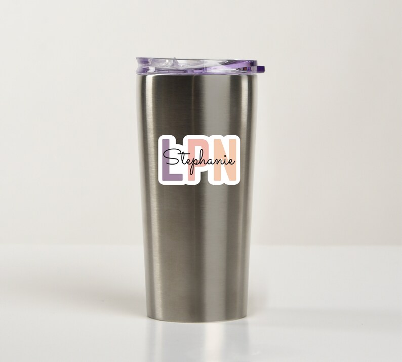 May include: A stainless steel tumbler with a purple lid and a sticker that says "LPN Stephanie" in colorful letters.