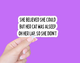 May include: A white sticker with black text that reads "She believed she could but her cat was asleep on her lap, so she didn't."