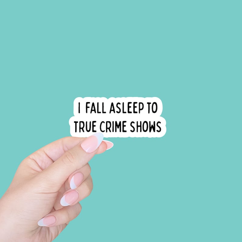 May include: A white sticker with black text that reads "I fall asleep to true crime shows". A hand is holding the sticker in front of a turquoise background.