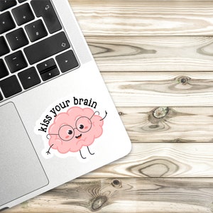 May include: A pink brain cartoon character wearing glasses with the text "kiss your brain" on a white sticker.