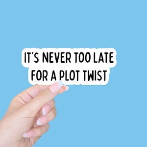 May include: A white sticker with black text that reads "It's never too late for a plot twist." A hand is holding the sticker.