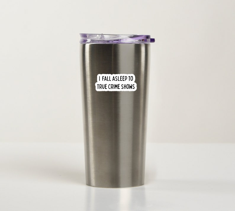 May include: Stainless steel travel mug with a purple lid and a white sticker that says "I fall asleep to true crime shows".