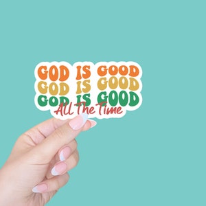 May include: A sticker with the text "God is good" repeated three times in green, orange, and yellow. The text "All the time" is written in red below the repeated text.