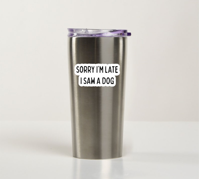 May include: A stainless steel travel mug with a purple lid and a white sticker that says "Sorry I'm late I saw a dog".
