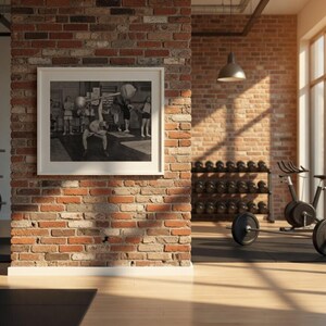 May include: A gym interior with exposed brick walls and hardwood floors. A framed black and white photo hangs on the wall. Exercise equipment includes a weight rack, dumbbells, a stationary bike, and a barbell with weights. A potted plant sits near a large window.