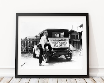 May include: A black and white photograph of a man standing next to a vintage car with a sign that reads "I'm not a Bootlegger DON'T SHOOT I'LL STOP".