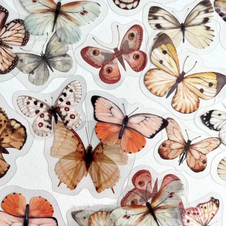 Op de afbeelding: Assortiment van kleurrijke vlinderstickers met verschillende vleugelpatronen en kleuren. De stickers zijn gedrukt op een transparante achtergrond.