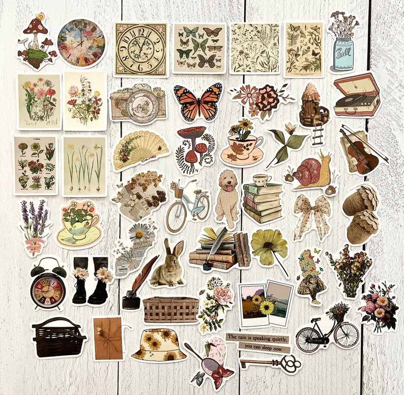 May include: A collection of vintage-style stickers featuring various designs, including flowers, butterflies, mushrooms, clocks, a snail, a rabbit, a basket, a book stack, a jar, a musical instrument, a teacup, a clock, a bicycle, and a quote about the rain. The stickers are on a white wooden background.