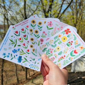 May include: Five sheets of watercolor flower stickers. The sheets feature different flower designs, including tulips, sunflowers, and wildflowers. The stickers are perfect for adding a touch of whimsy to journals, planners, and other craft projects.