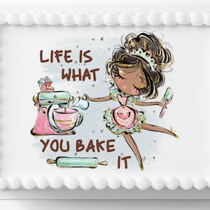 May include: A white cake with a frosting border and a printed image of a girl in a pink and green dress holding a spatula. The image also includes a stand mixer, a rolling pin, and the text "Life is what you bake it."