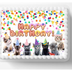 May include: A rectangular birthday cake with white frosting and a decorative border. The cake features the words "HAPPY BIRTHDAY!" in colorful letters, with images of kittens wearing party hats. Colorful confetti and pennants decorate the top of the cake.