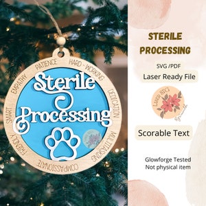 May include: A wooden Christmas ornament with the words "Sterile Processing" in white script on a blue background. The ornament includes a paw print and words like "Patience" and "Dedication". It is hanging on a Christmas tree.
