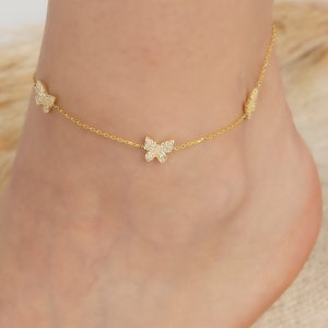 Puede incluir: Tobillera dorada con tres dijes de mariposa, cada dije está incrustado con diamantes de imitación transparentes.