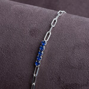 May include: A silver chain bracelet with a row of blue gemstones.