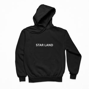 May include: Black hoodie with a hood and a front pocket. The text "STAR LAND" is printed in white across the chest. The hoodie is made of a soft material.