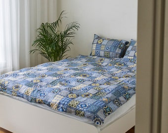 Set of three linens. Duvet cover and two pillowcases made of linen. Blue squares appear in a print cloth pattern, patterned linen