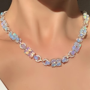 May include: A silver necklace featuring iridescent oval-shaped stones set in a delicate chain. The stones have a rainbow-like shimmer.