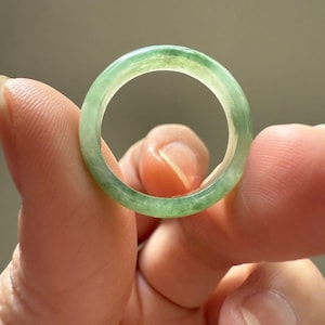 Op de afbeelding: Een groene jade ring met een gladde, gepolijste afwerking. De ring is dik en heeft een afgeronde vorm.