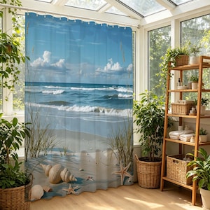 May include: A shower curtain featuring a beach scene with blue ocean waves, a sandy shore, and a bright blue sky with fluffy white clouds. Seashells and starfish are scattered on the sand. The curtain is hung in a bright, sunlit room.