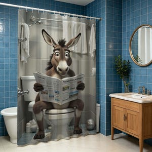 May include: A shower curtain featuring a brown donkey with large ears and wide eyes sitting on a white toilet while reading a newspaper titled Morutto Poibert. The curtain depicts a tiled bathroom interior with white towels hanging on a rack.