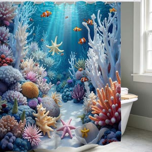 May include: A colourful shower curtain depicting an underwater scene with coral, starfish, and clownfish. The design features shades of blue, white, orange, pink, and purple, creating a lively bathroom decor.